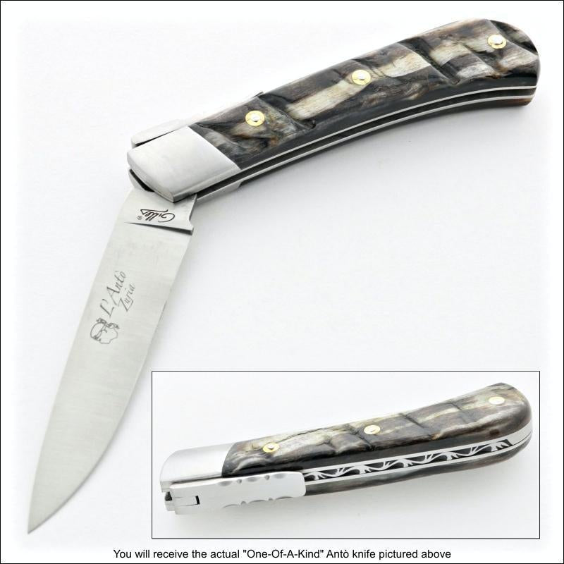a couple view of a Corsican L' Antò 12 cm pocket knife with dark ram horn handle. one view is partially open and the other shows the file work and lock-top trigger. 