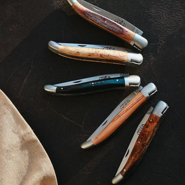 several 11 cm laguiole pocket knives in the close position on a black background