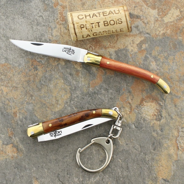 2 forge de laguiole 7 cm handle penknives on a ston next to a cork to show size perspective