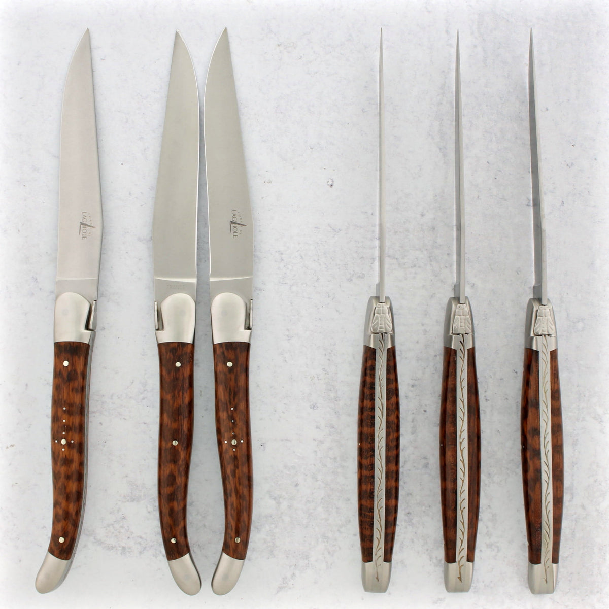 Set of six knives with amourette handles on a textured white background