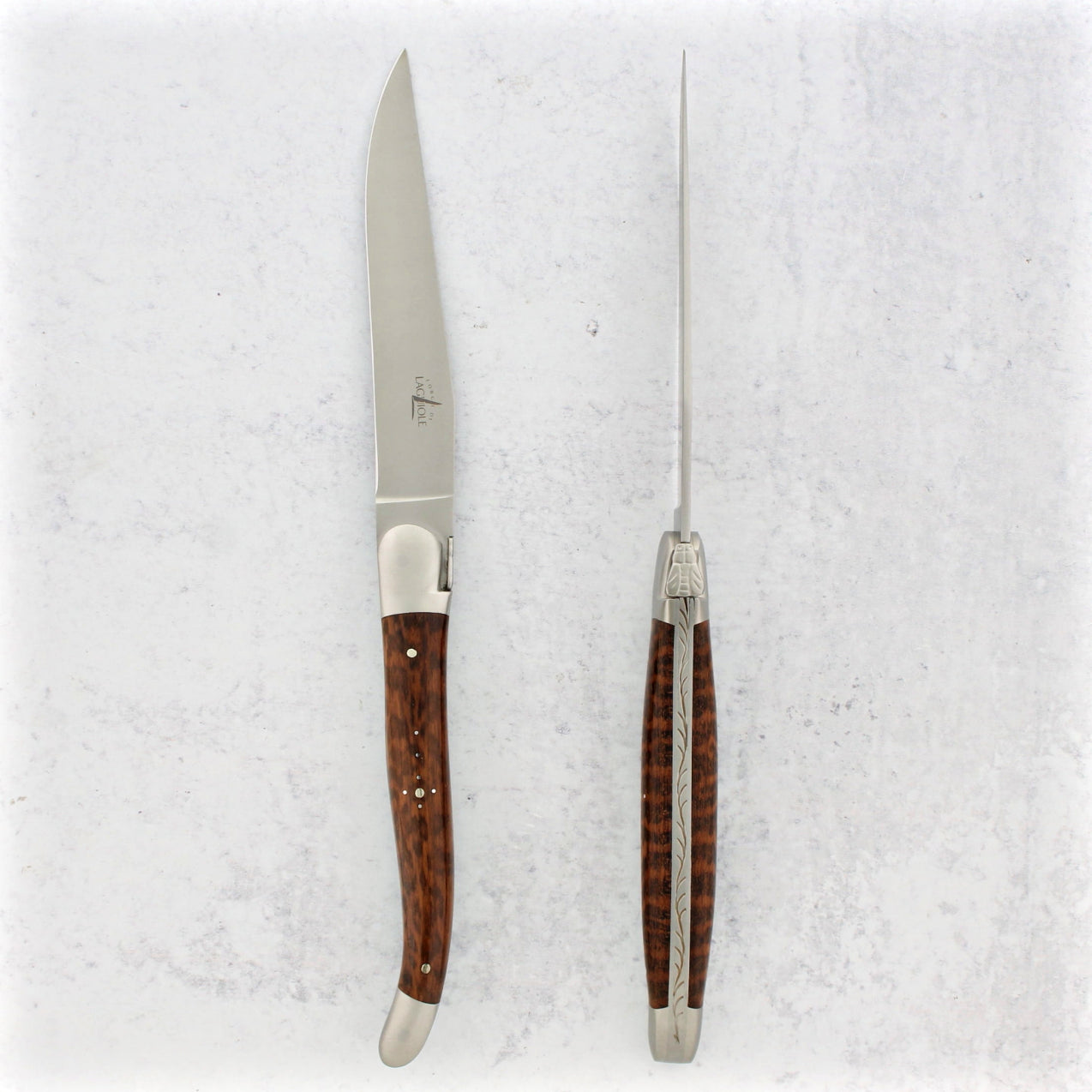 Set of six knives with amourette handles on a textured white background