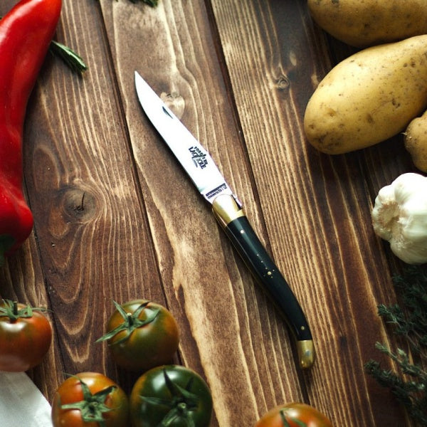 open forge de laguiole pocket knives show next to vegetables on a wooden surface