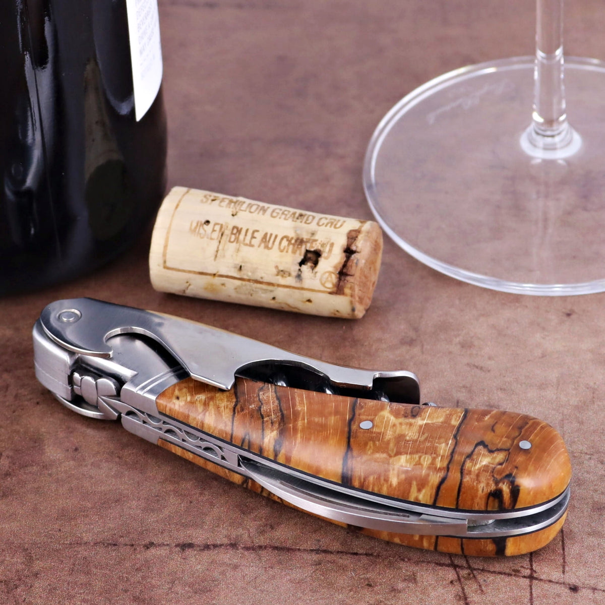 Laguiole Magnum Burled Beech End Grain Corkscrew, close-up of handle with wood grain, cork, and wine glass.