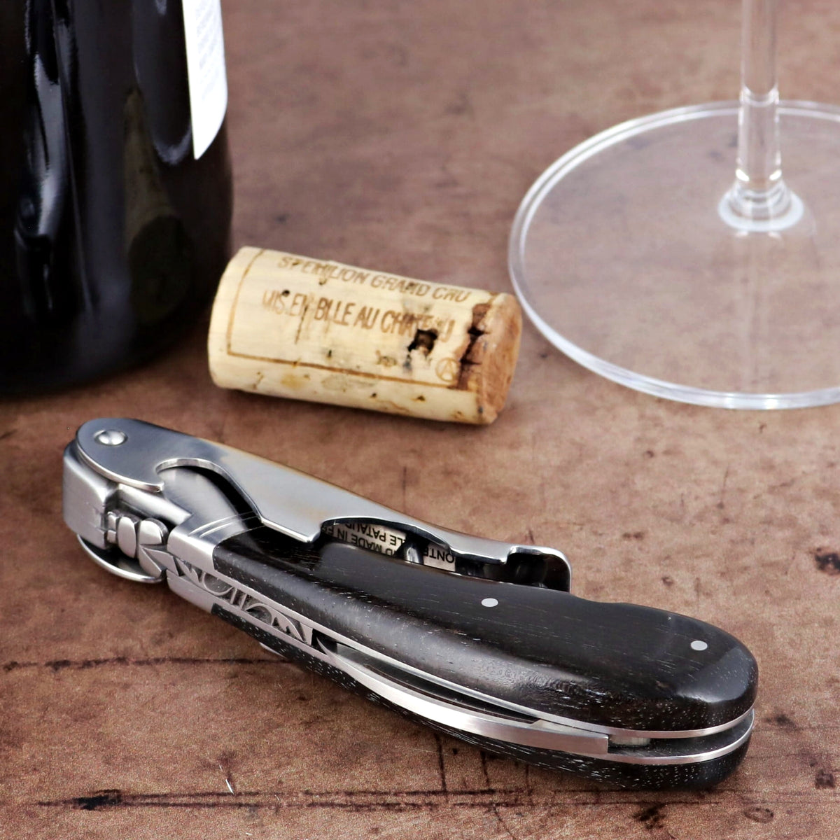 Laguiole Magnum Ebony Corkscrew, side view, dark ebony handle with silver accents, on a wooden surface.
