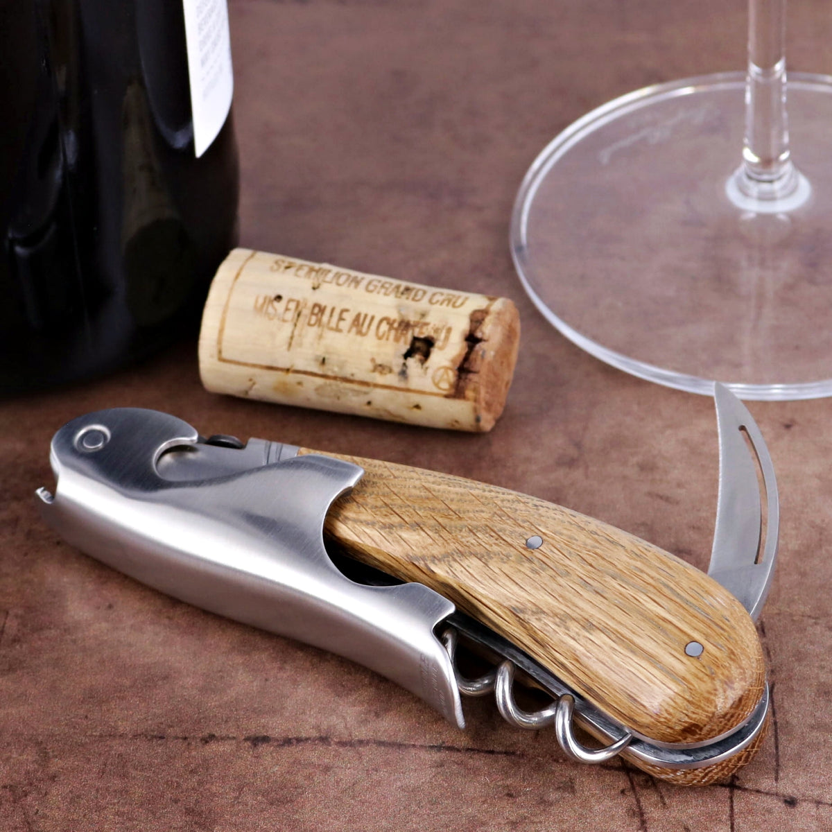 Laguiole Magnum Oak Barrel Wood Corkscrew, side view, with wine bottle, cork, and glass.