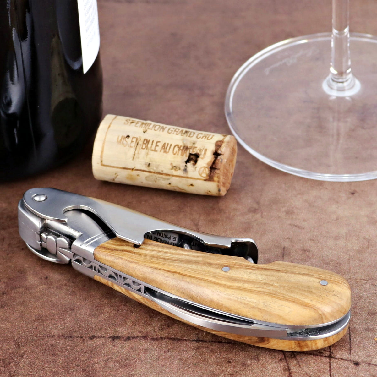 Laguiole Magnum Olive Wood Corkscrew, close-up of handle with stainless steel and natural wood grain.