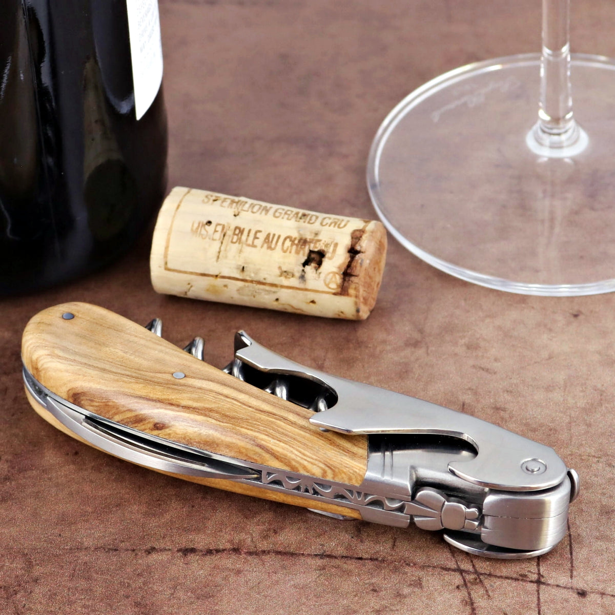 Laguiole Magnum Olive Wood Corkscrew, close-up of folded corkscrew with wood handle and metal accents.