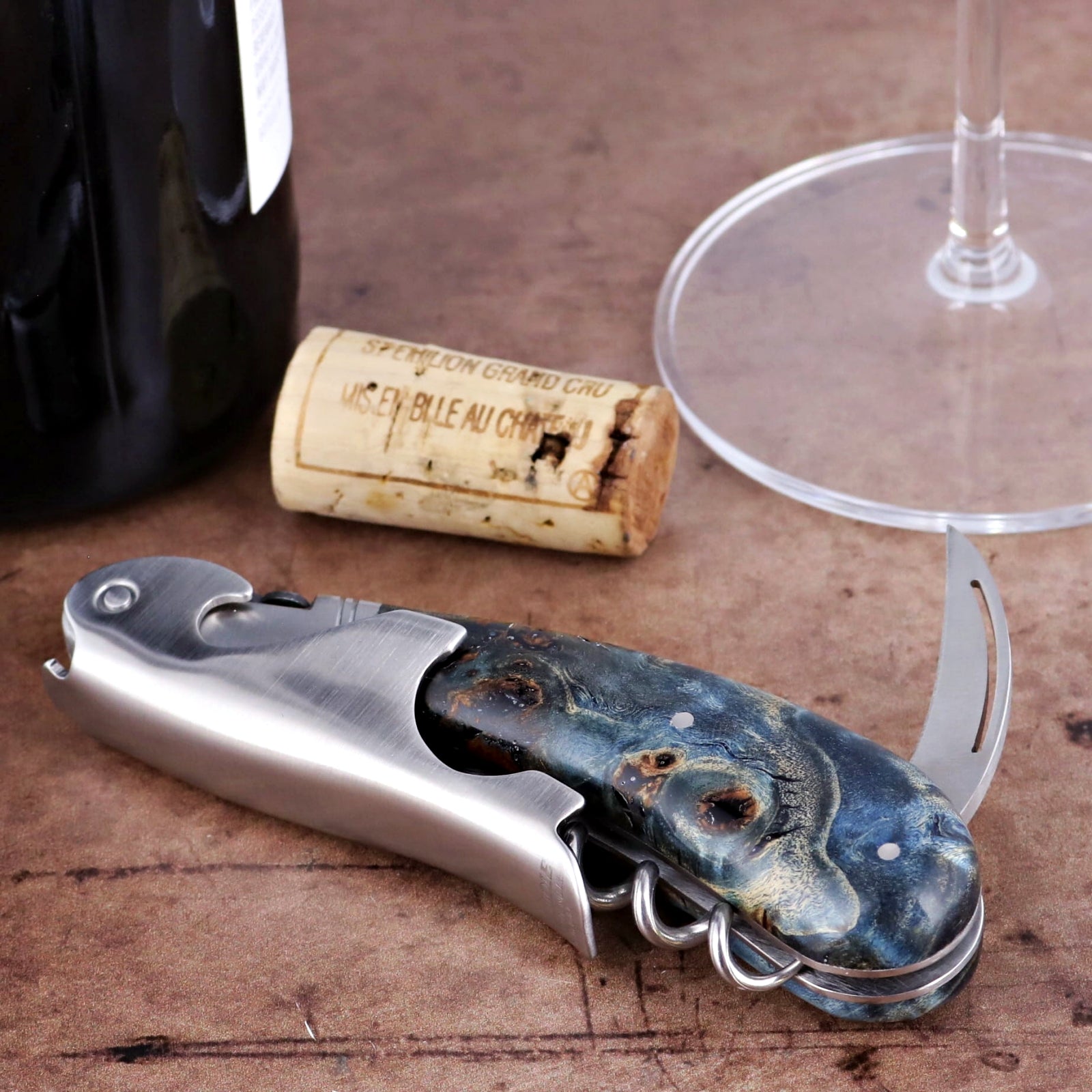 Laguiole Magnum Corkscrew, blue stained poplar burl handle, side view with wine bottle and cork.
