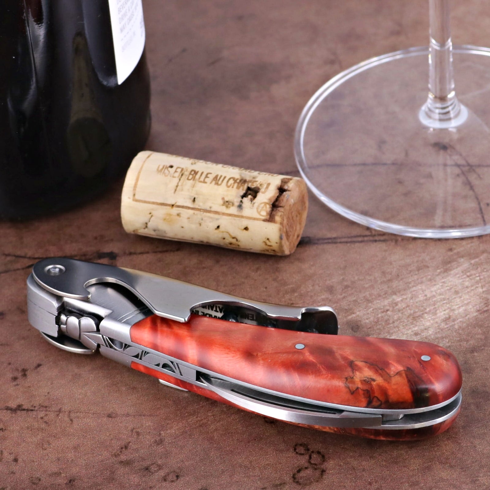 Laguiole Magnum Corkscrew Red, stained poplar burl handle, side view with cork and wine glass.