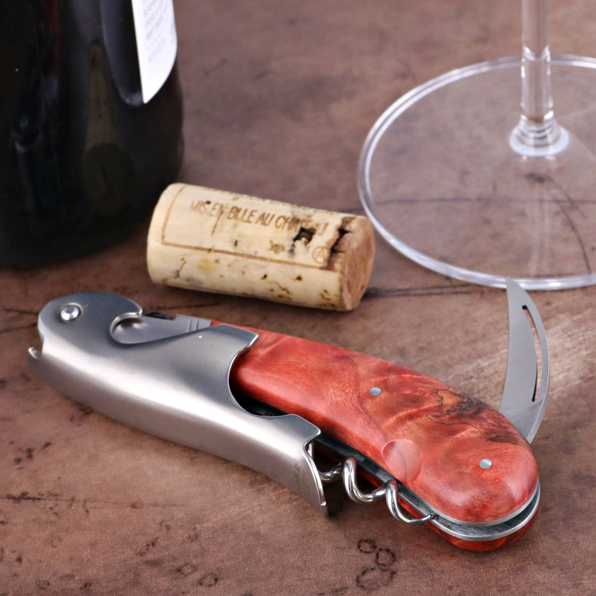 Laguiole Magnum Corkscrew Red, stained poplar burl handle, side view with cork and wine glass.