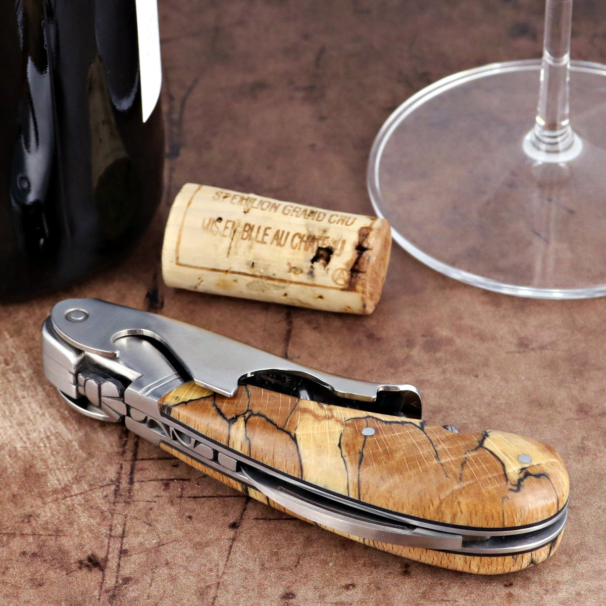 Laguiole Magnum Burled Beech Corkscrew, close-up of folded stainless steel tool with wood handle.