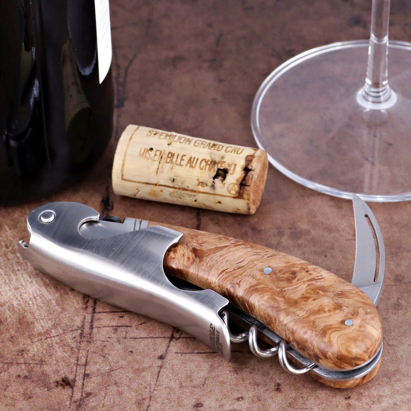 Laguiole Magnum Burled Teak Corkscrew close-up featuring a polished steel body and wood grain handle.