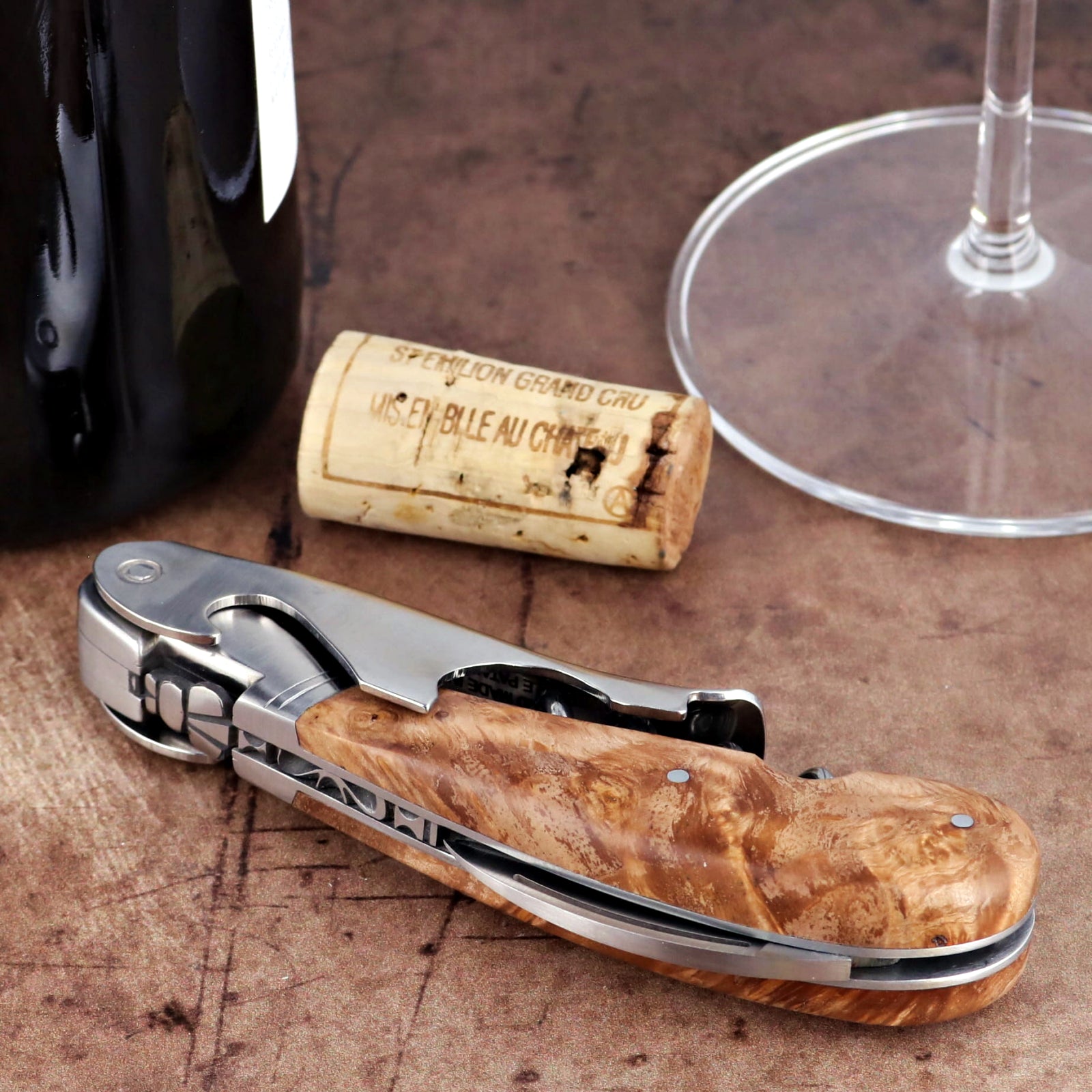 Laguiole Magnum Burled Teak Corkscrew close-up featuring a polished steel body and wood grain handle.