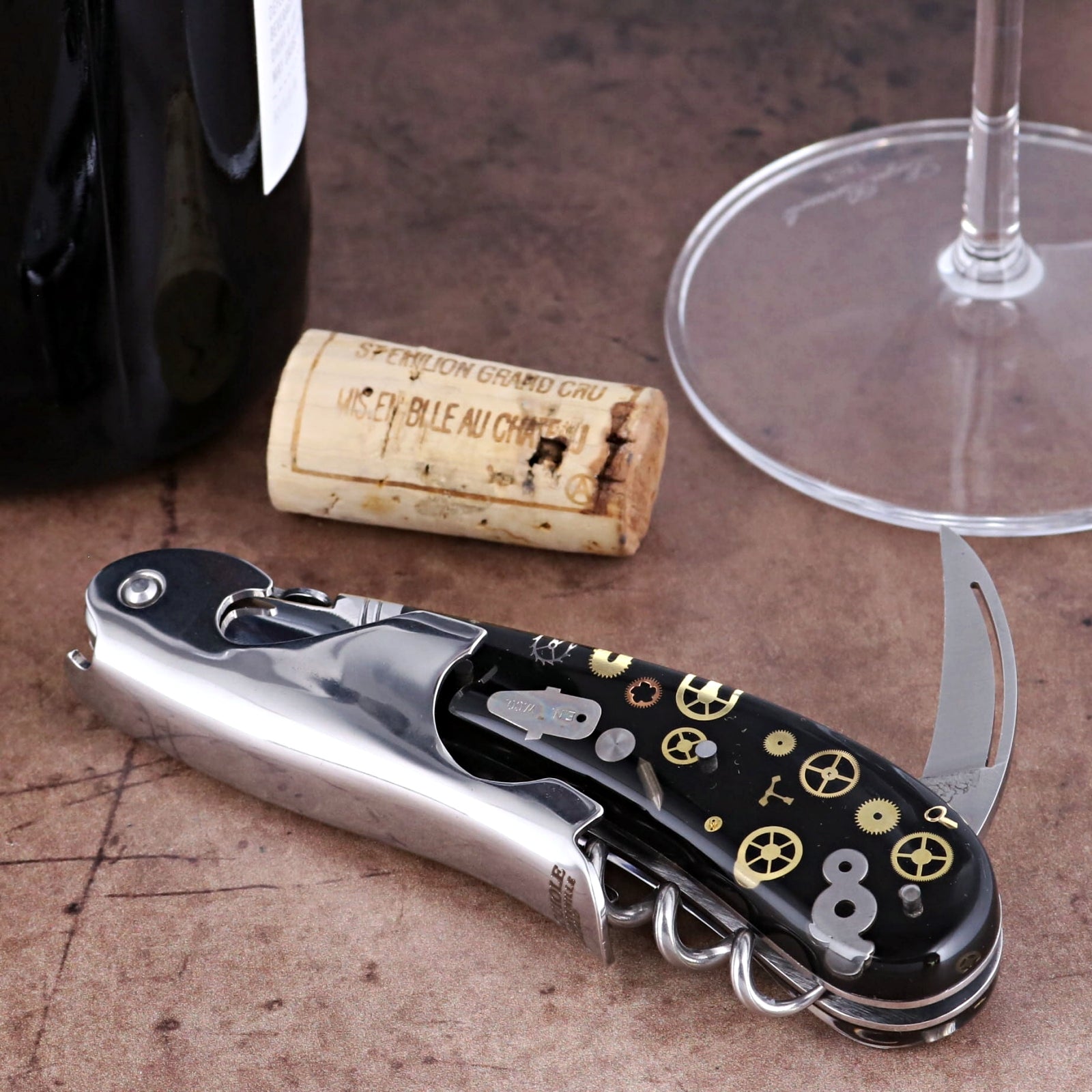 Laguiole Magnum Corkscrew close-up showing polished steel and black handle with gold gear inlays.