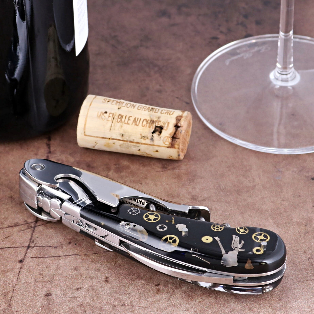 Laguiole Magnum Corkscrew close-up featuring a black handle with intricate gold timepiece gear inlays.