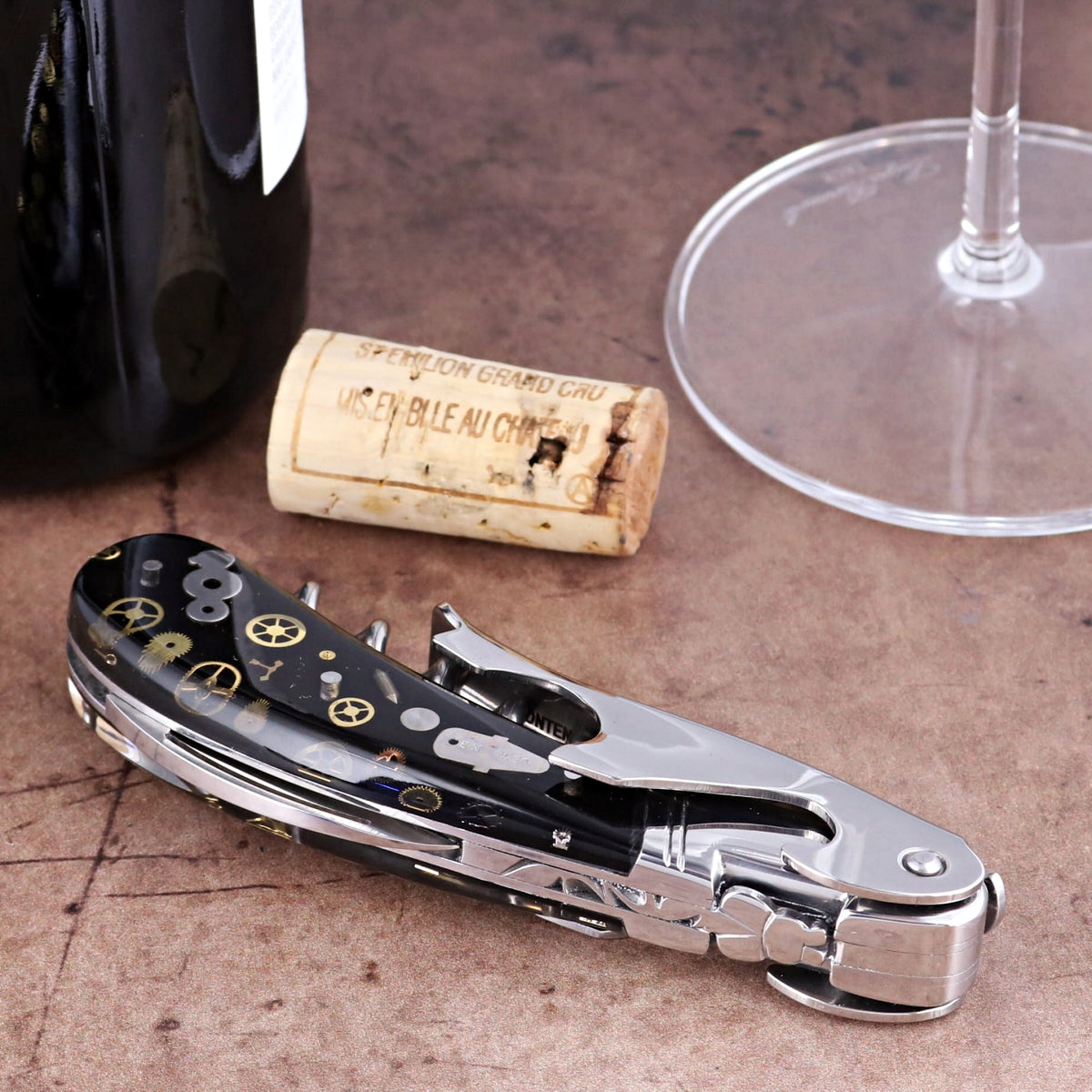 Laguiole Magnum Corkscrew close-up featuring a black handle with intricate gold timepiece gear inlays.