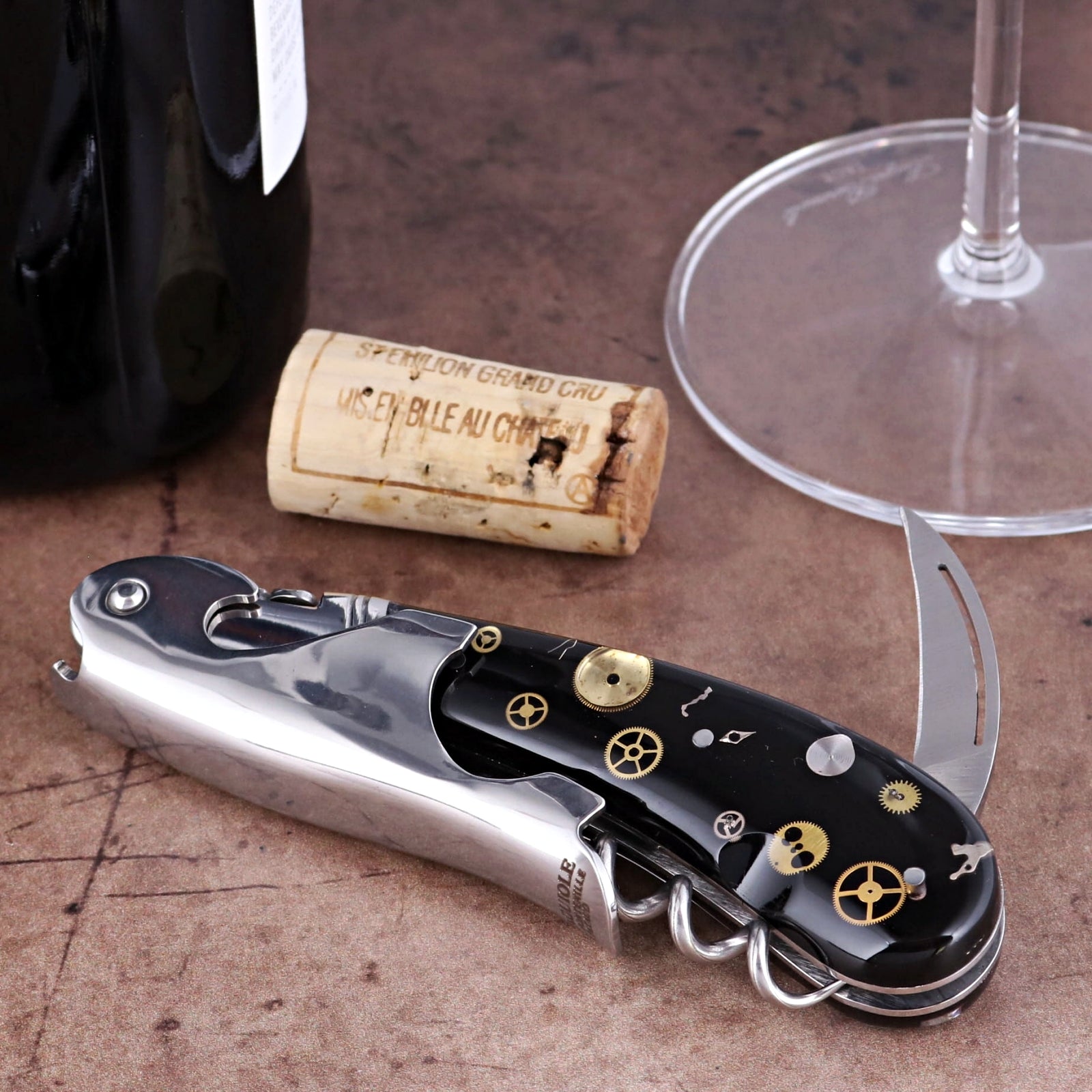 Laguiole Magnum Corkscrew close-up showing black handle with intricate gold timepiece gear inlays.