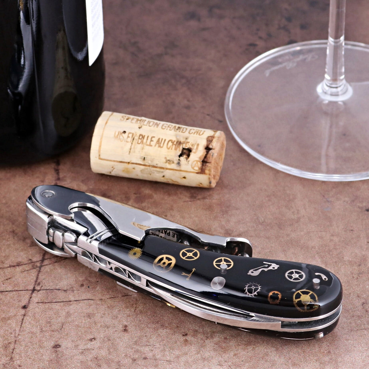 Laguiole Magnum Corkscrew close-up featuring a black handle with intricate gold timepiece gear inlays.