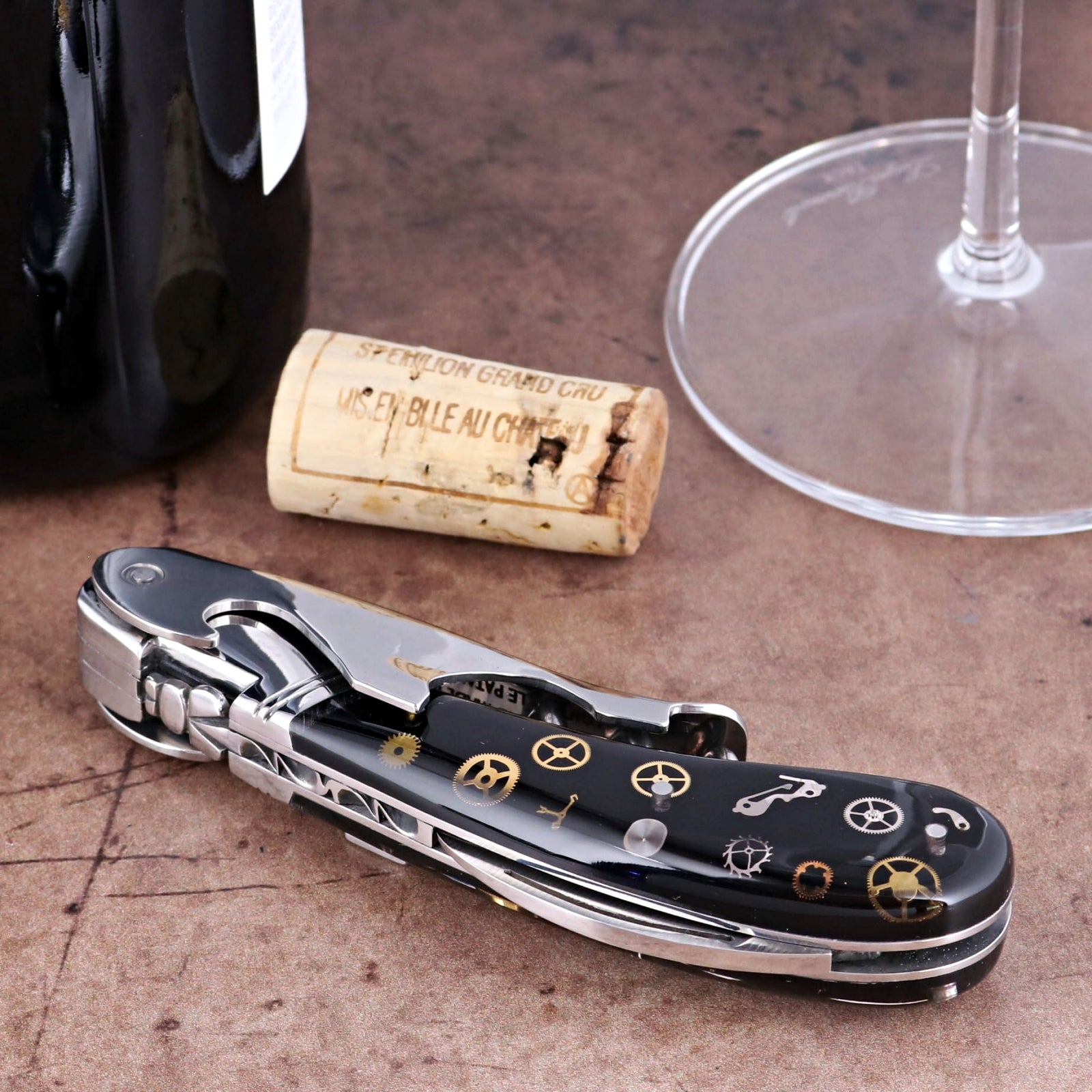 Laguiole Magnum Corkscrew close-up showing black handle with intricate gold timepiece gear inlays.