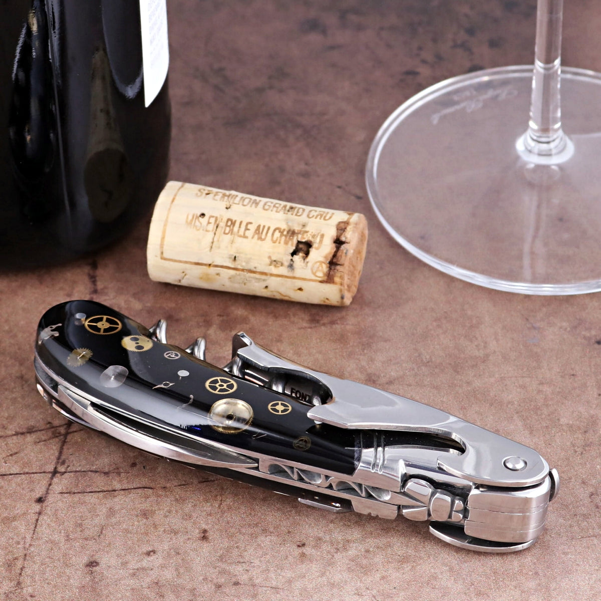 Laguiole Magnum Corkscrew close-up featuring a black handle with intricate gold timepiece gear inlays.