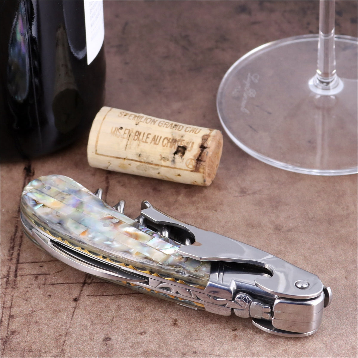 Laguiole Magnum Mother of Pearl corkscrew, close-up of iridescent handle with ornate metal detailing.