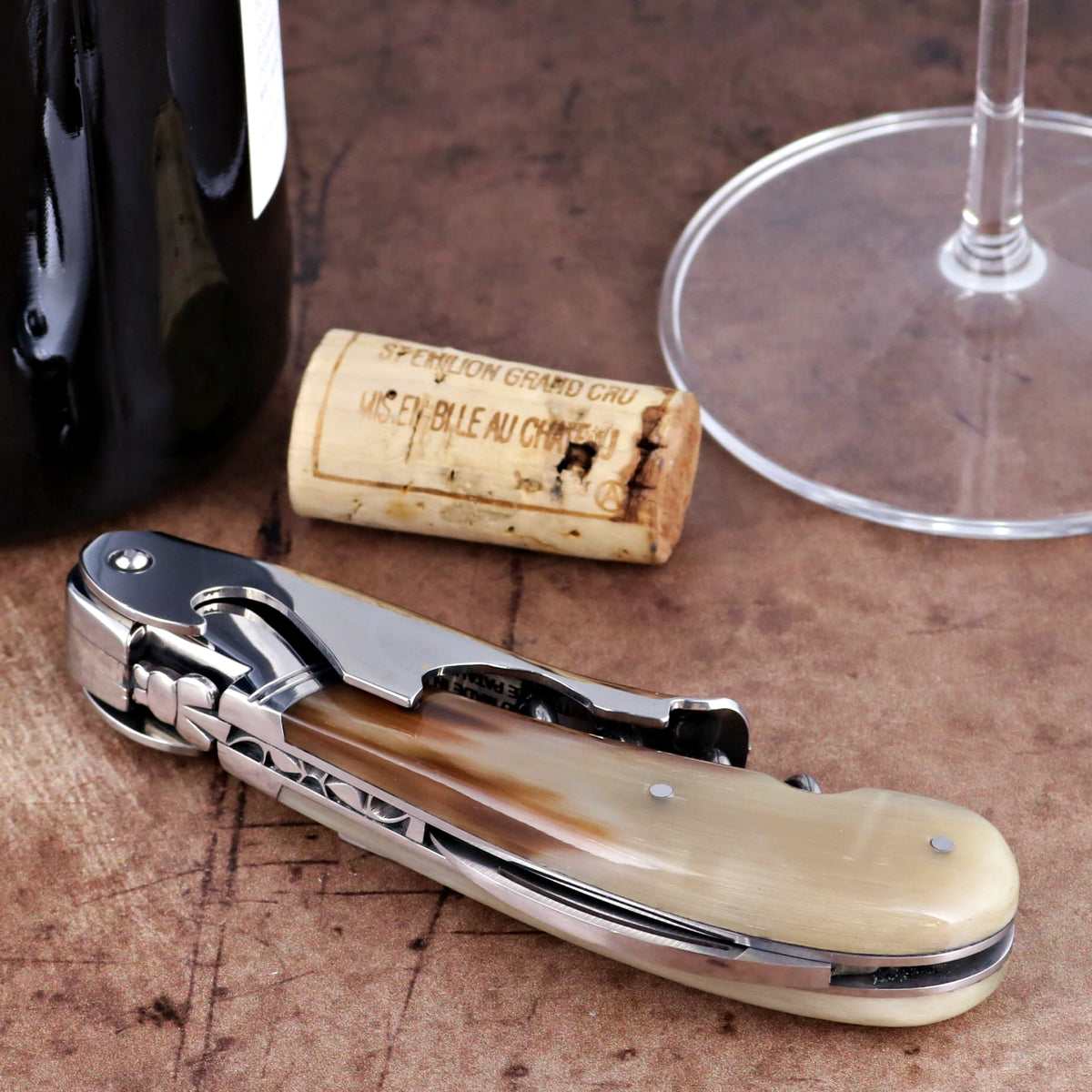 Laguiole Magnum Horn Tip Corkscrew, close-up of polished horn handle and steel frame on wood surface.