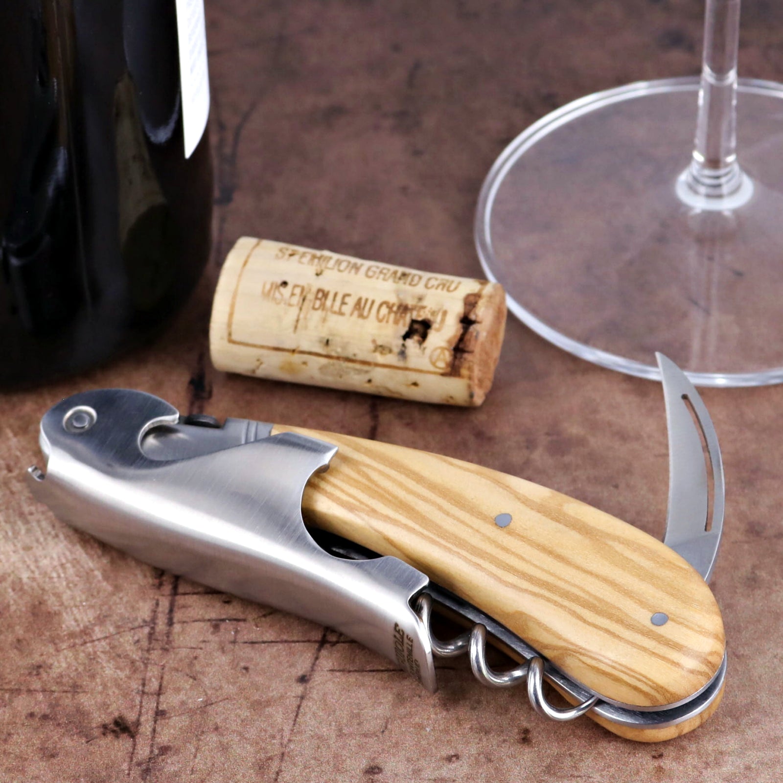 Laguiole Magnum Olive Wood Corkscrew close-up featuring a polished steel body and wood grain handle.