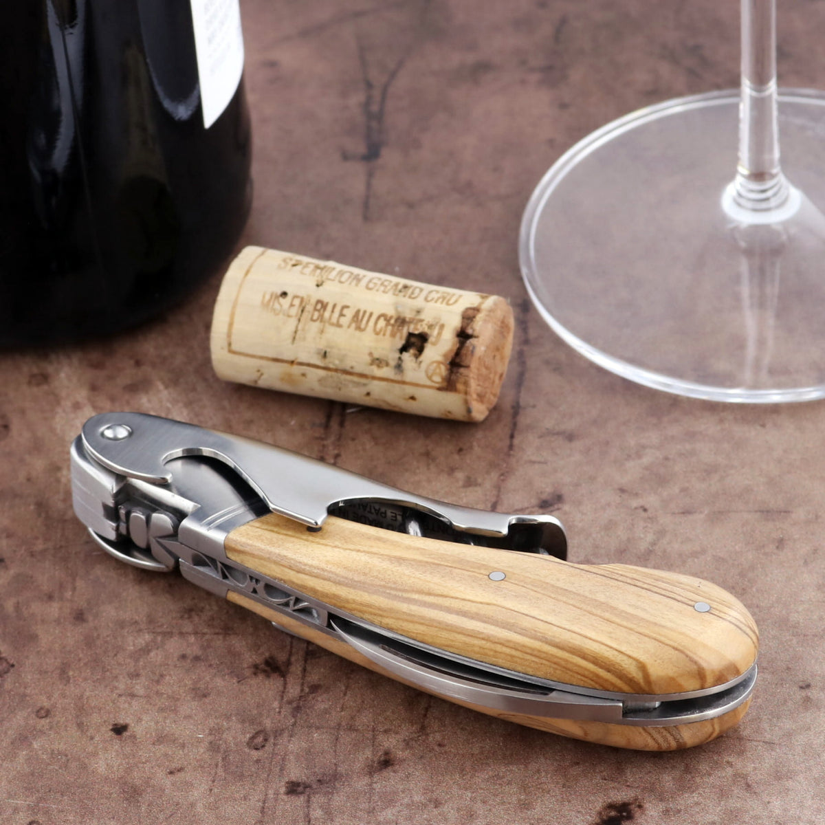 Laguiole Magnum Olive Wood Corkscrew, close-up side view, natural wood handle, stainless steel accents.