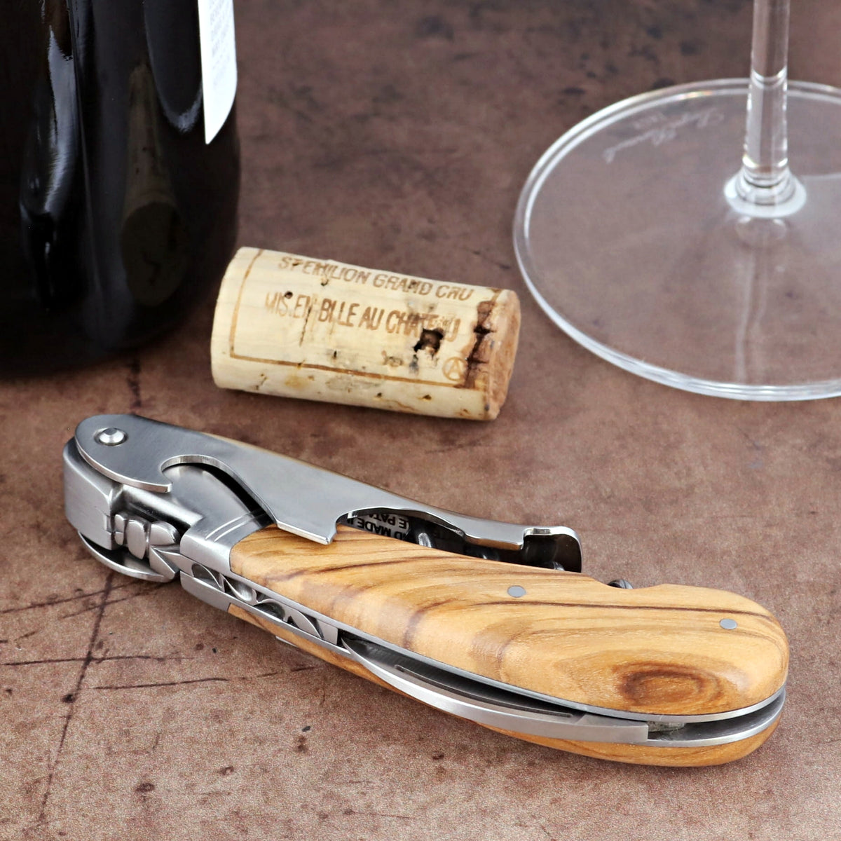 Laguiole Magnum Olive Wood Corkscrew, close-up side view showing polished steel and wood grain handle.