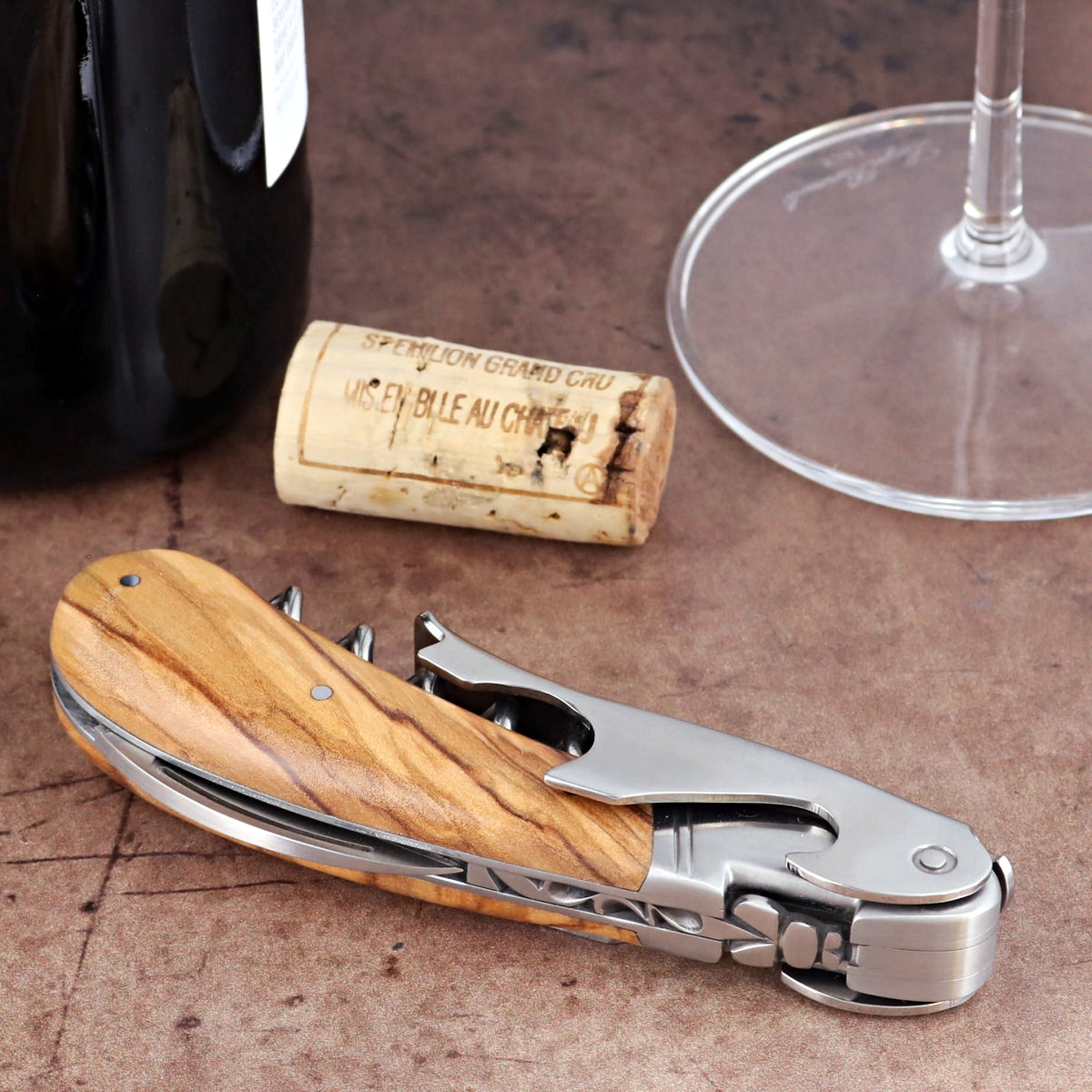 Laguiole Magnum Olive Wood Corkscrew, close-up side view showing polished steel and wood grain handle.