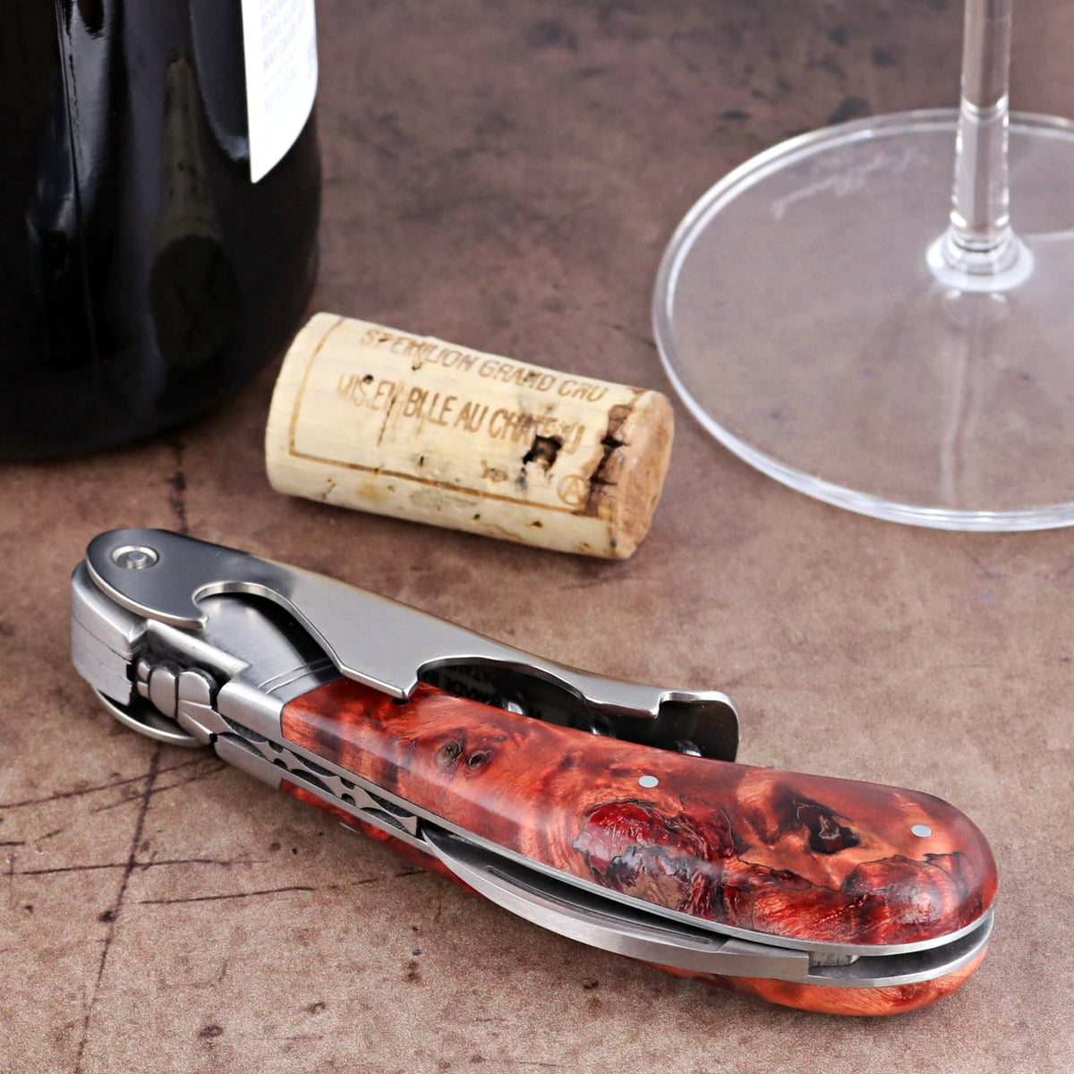 Laguiole Magnum red stained poplar burl corkscrew, close-up side view showing polished steel detail.