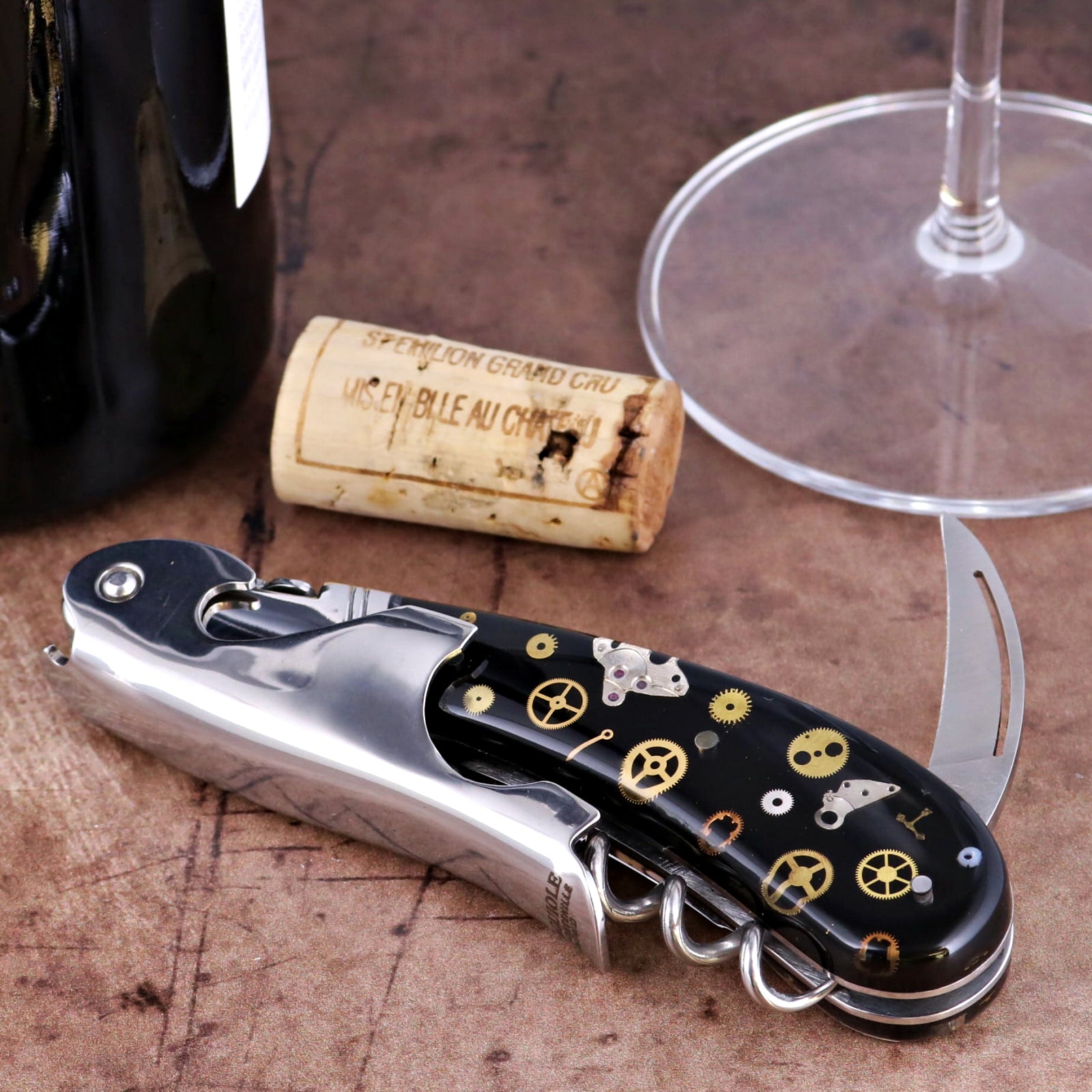 Laguiole Magnum Corkscrew close-up featuring a black handle with intricate gold timepiece gear inlays.