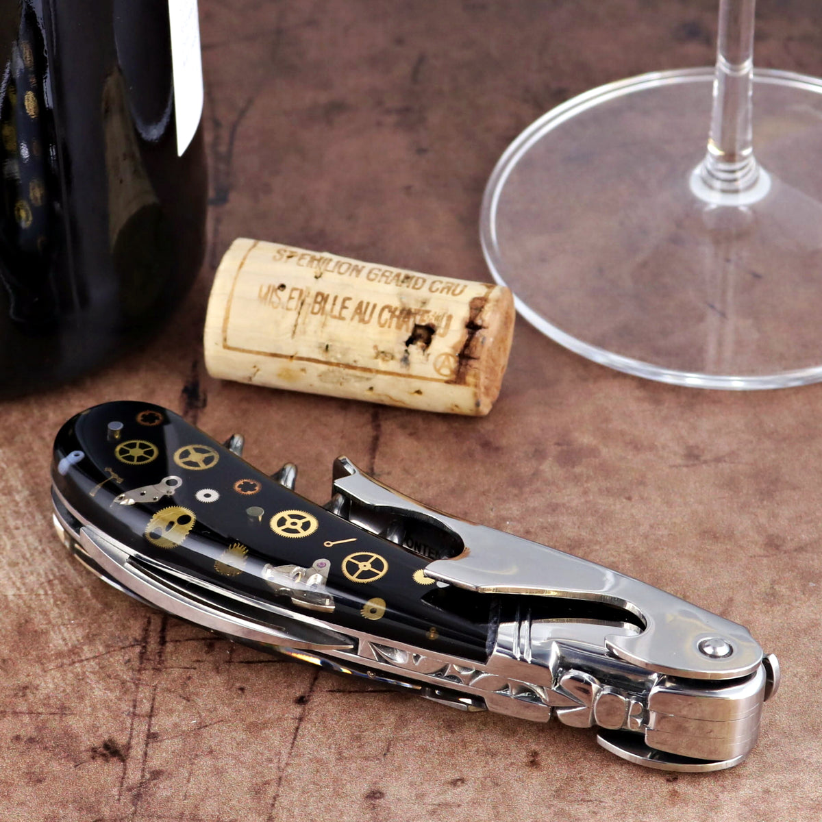 Laguiole Magnum Corkscrew close-up, featuring a black handle with intricate gold timepiece gear inlay.