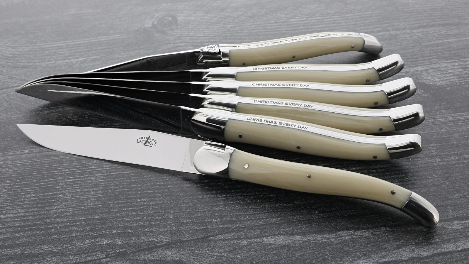 a set of 6 forge de Laguiole 6 Piece Steak Knife Set Opalescence handle on a dark grey wood background
