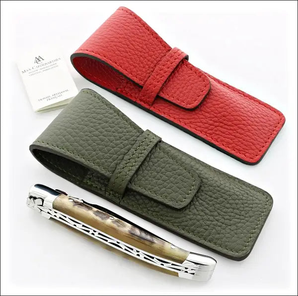 top view of 1 red and 1 green leather sheath next to a closed laguiole knife folding knife with ram horn handle material