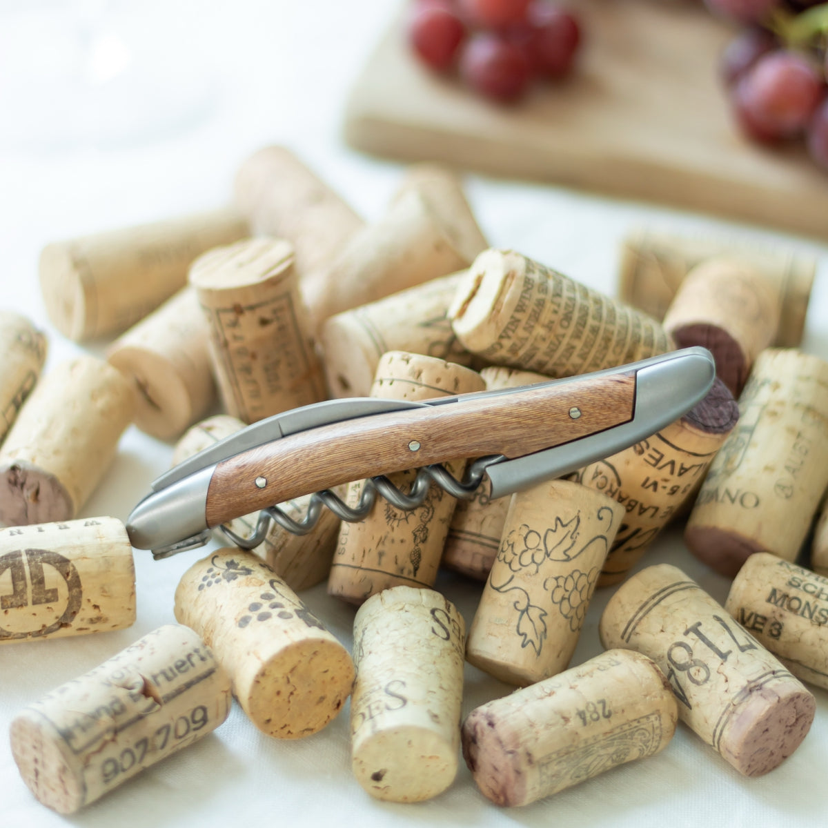 Forge de Laguiole Corkscrew, close-up of vine wood handle and satin finish resting on wine corks.