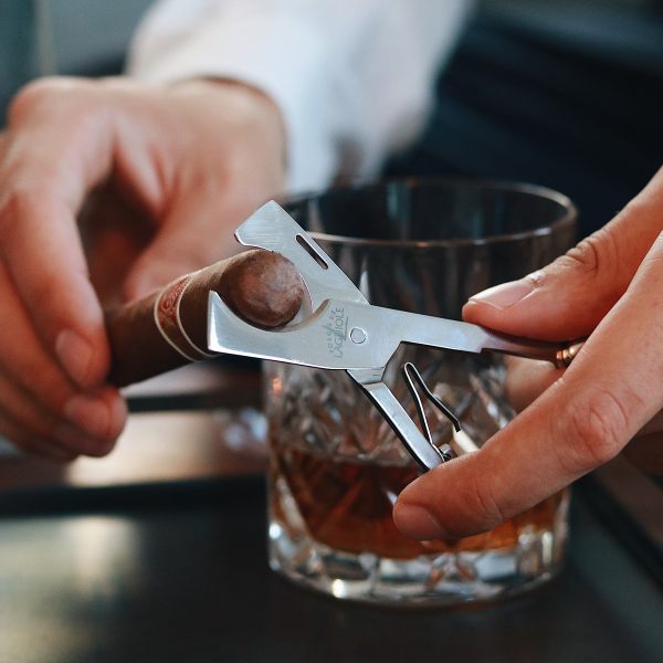 forge de laguiole cigar cutter and whisky glass - hands using the toll to demonstrate cutting a cigar