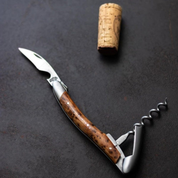 top view of a forge de laguiole corkscrew thuya handle with a cork on a black surface