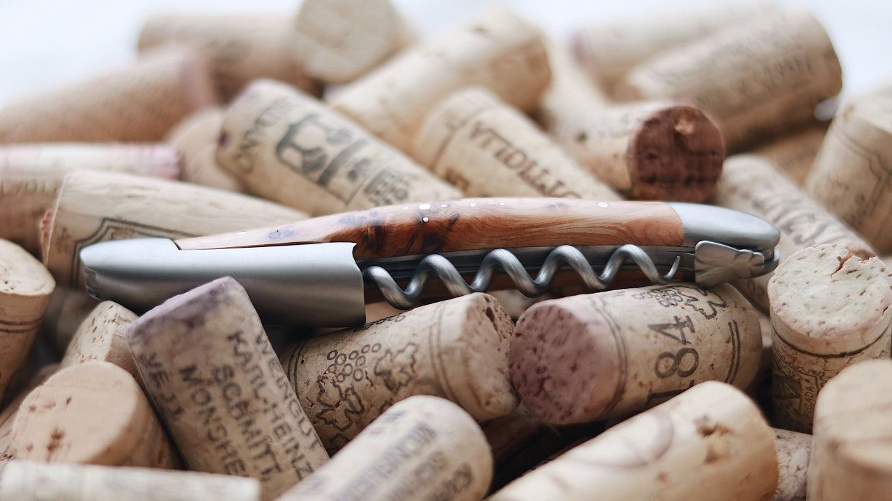 forge de laguiole corkscrew on top of several wine corks